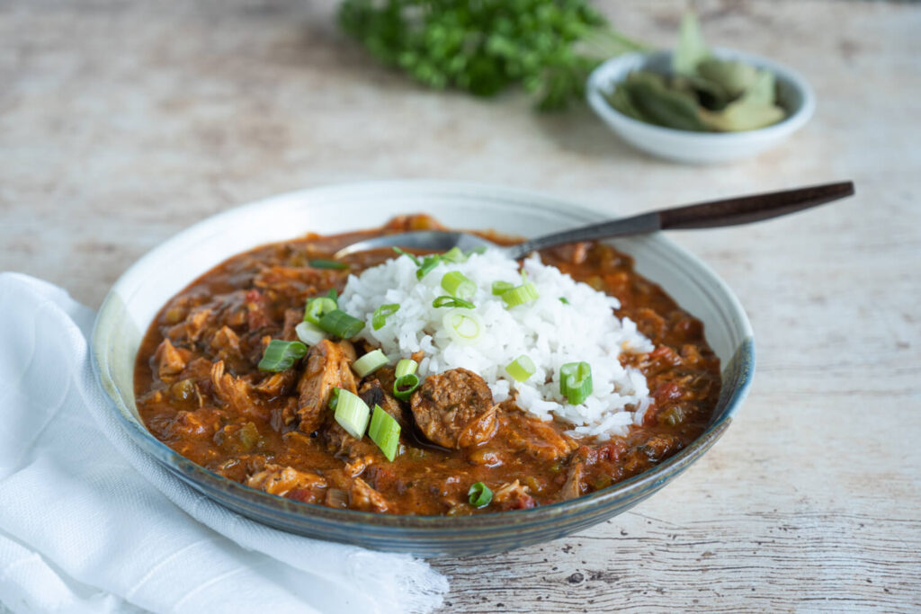 Bowl of turkey sausage gumbo served with white rice and garnished with fresh green oniions