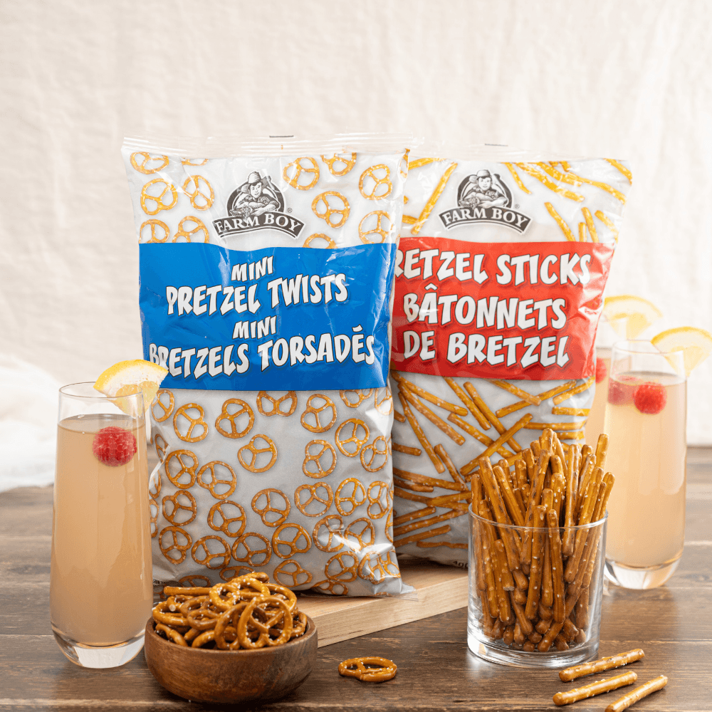 Bag of Farm Boy Mini Pretzel Twists and Farm Boy Pretzel Rods with loose pretzels and two glasses of cranberry lemonade