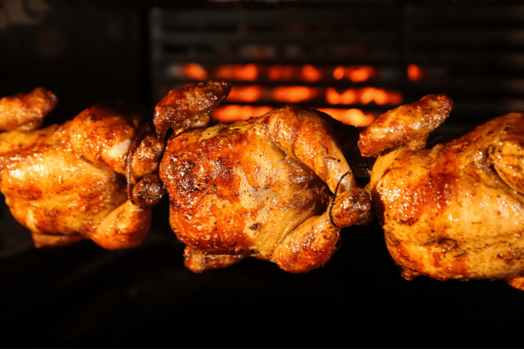 Grilling whole chickens in rotisserie machine, closeup