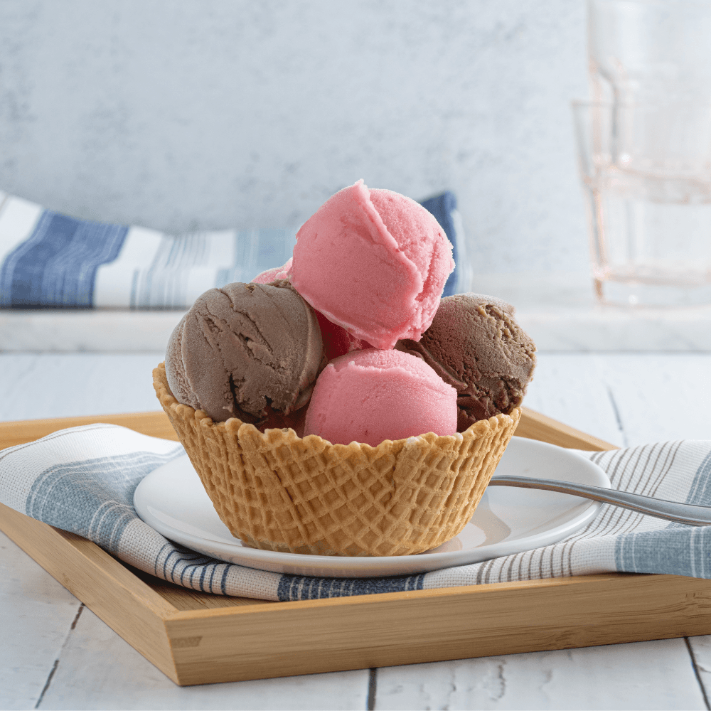 Multiple scoops of raspberry sorbet and chocolate gelato in waffle bowl on plate