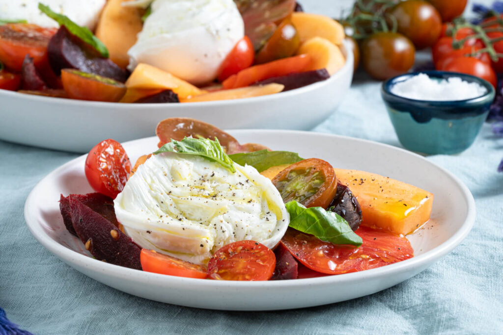 Plate of heirloom tomato, beet, and cantaloupe salad with burrata