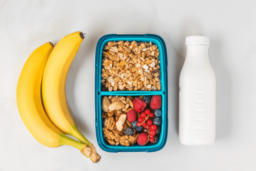 Healthy lunch box with granola, nuts, berries, banana and yogurt to make healthy breakfast on white background. top view