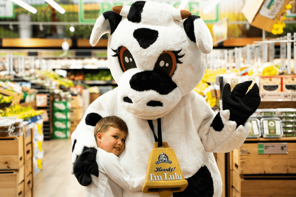 Small boy hugging Lulu the Cow the Farm Boy Mascot inside a Farm Boy store