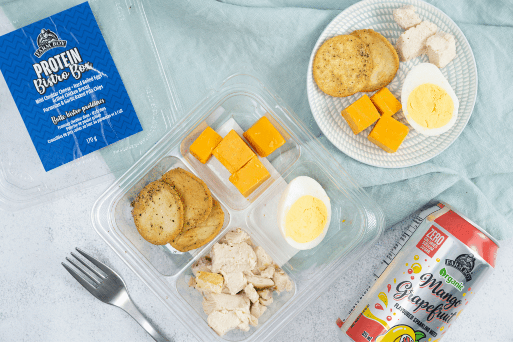Top view of Farm Boy Protein Bistro Box with cheddar cheese, hard boiled eggs, roasted chicken, and crackers
